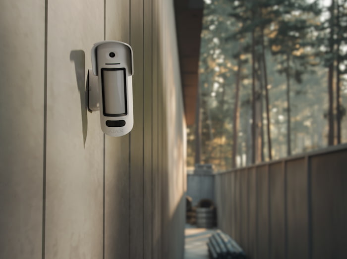 Ajax outdoor motion detector installed on a warehouse exterior wall for perimeter protection