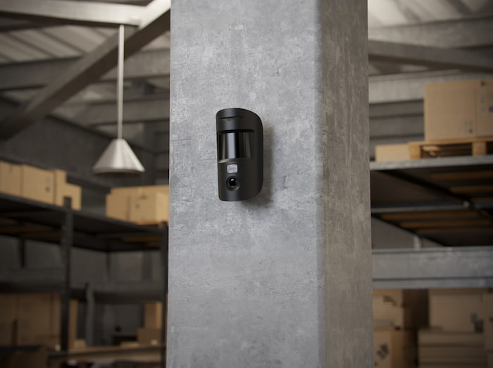 Ajax motion detector with photo verification installed inside a warehouse storage area