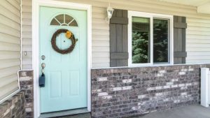 Front of a home with a green door and white siding