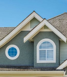 Close-up of the second story of a teal house with custom-sized windows