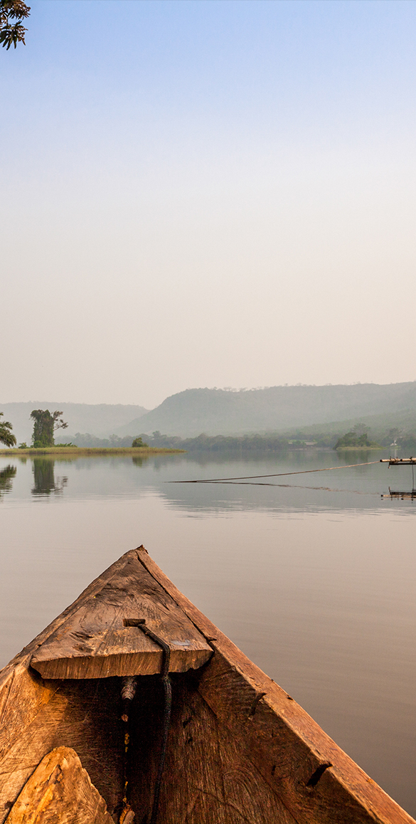 A wooden canoe bow on a calm misty lake at sunrise