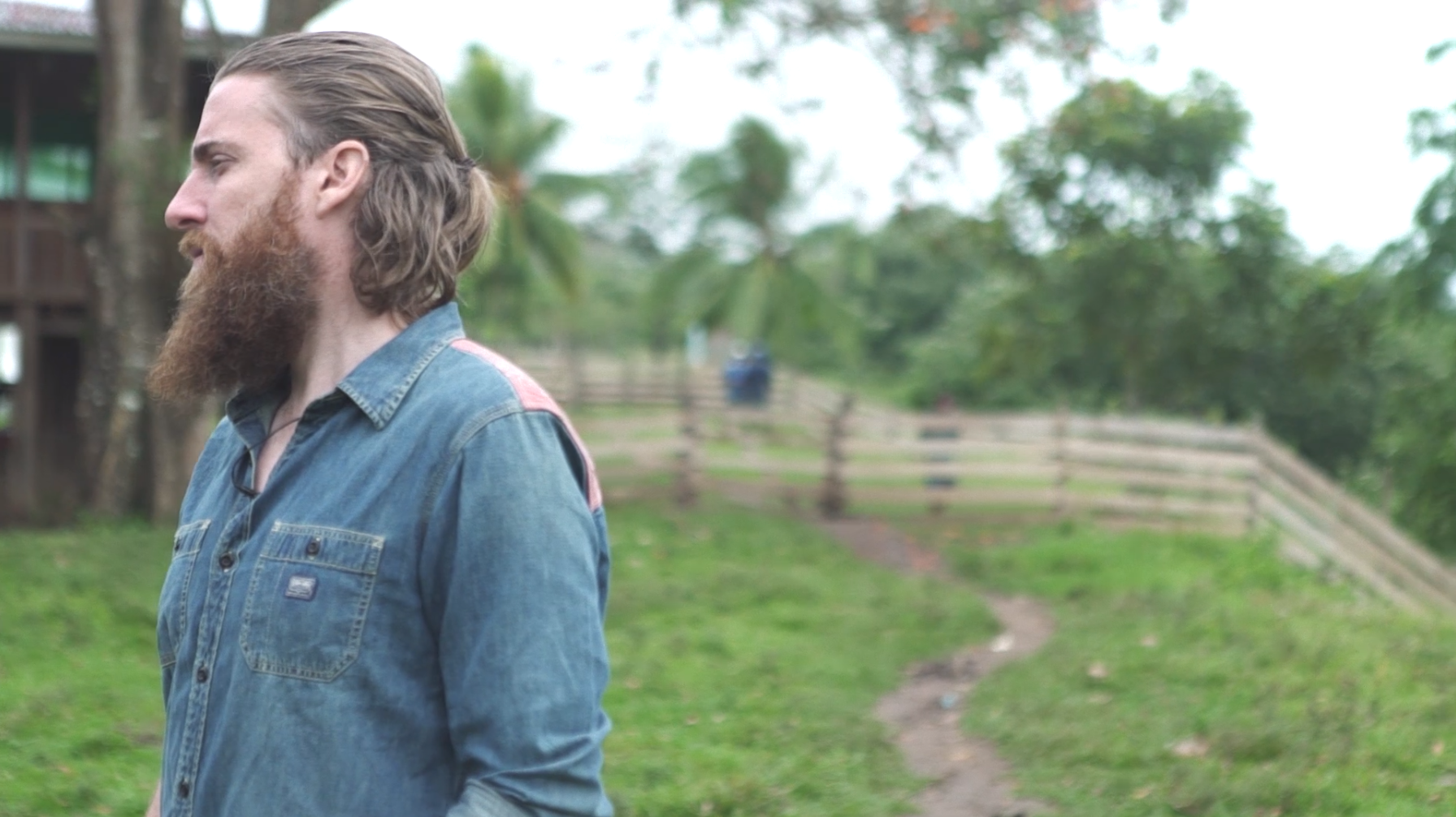 Adam Asher in a denim shirt looking out over a green hillside