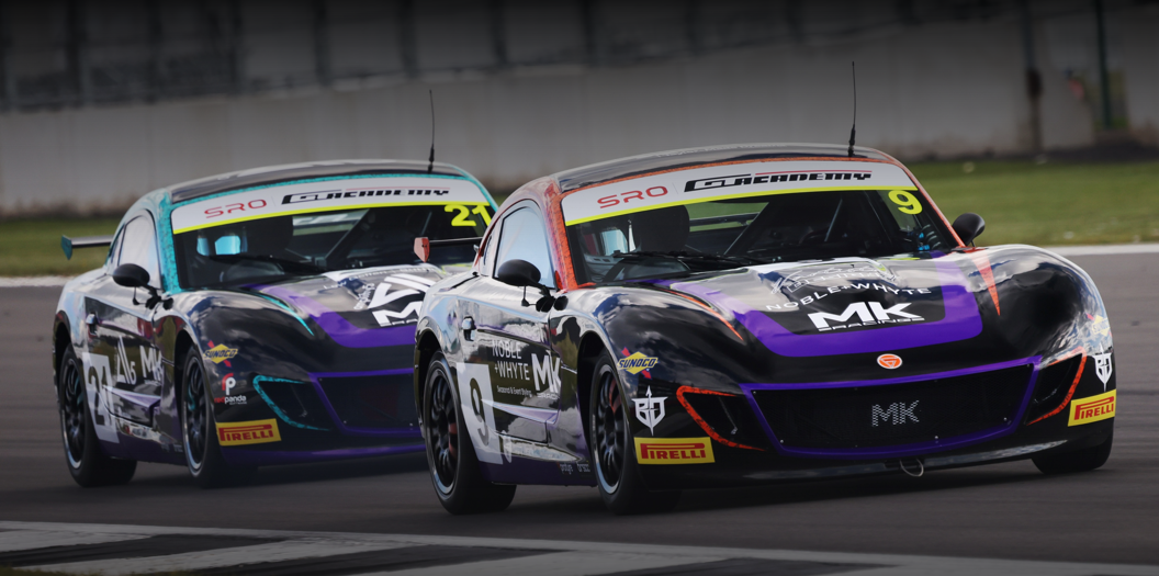 Two black and purple race cars with number 9 and 21 on a track during a race.