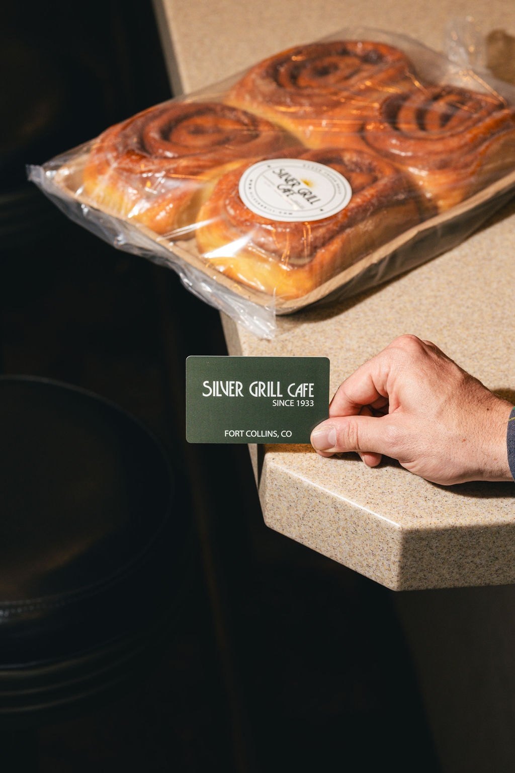 An image of a gift card next to a four pack of the world famous silver grill cinnamon rolls.