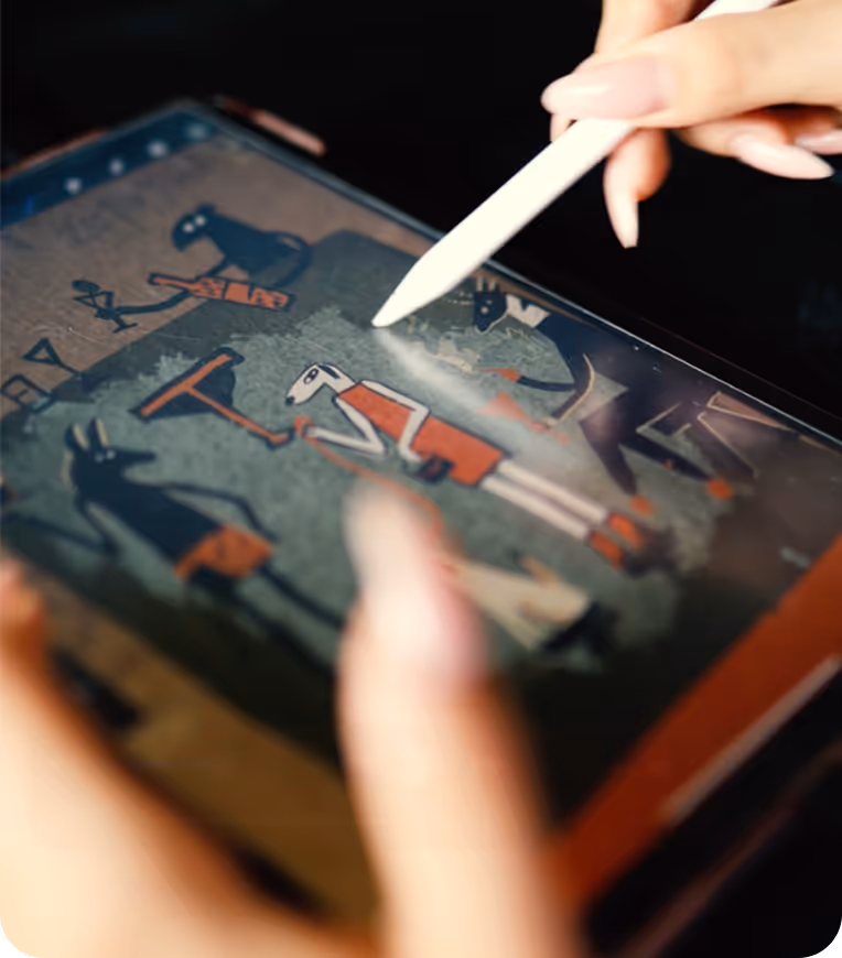 Hand holding a stylus drawing cartoon-style figures on a digital tablet screen.