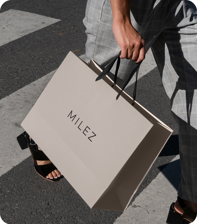 Open menu with a green page listing vitamin juices and prices in Serbian, next to a cartoon black fox wearing red boots holding a glass, on a wooden table with a person's hand nearby.