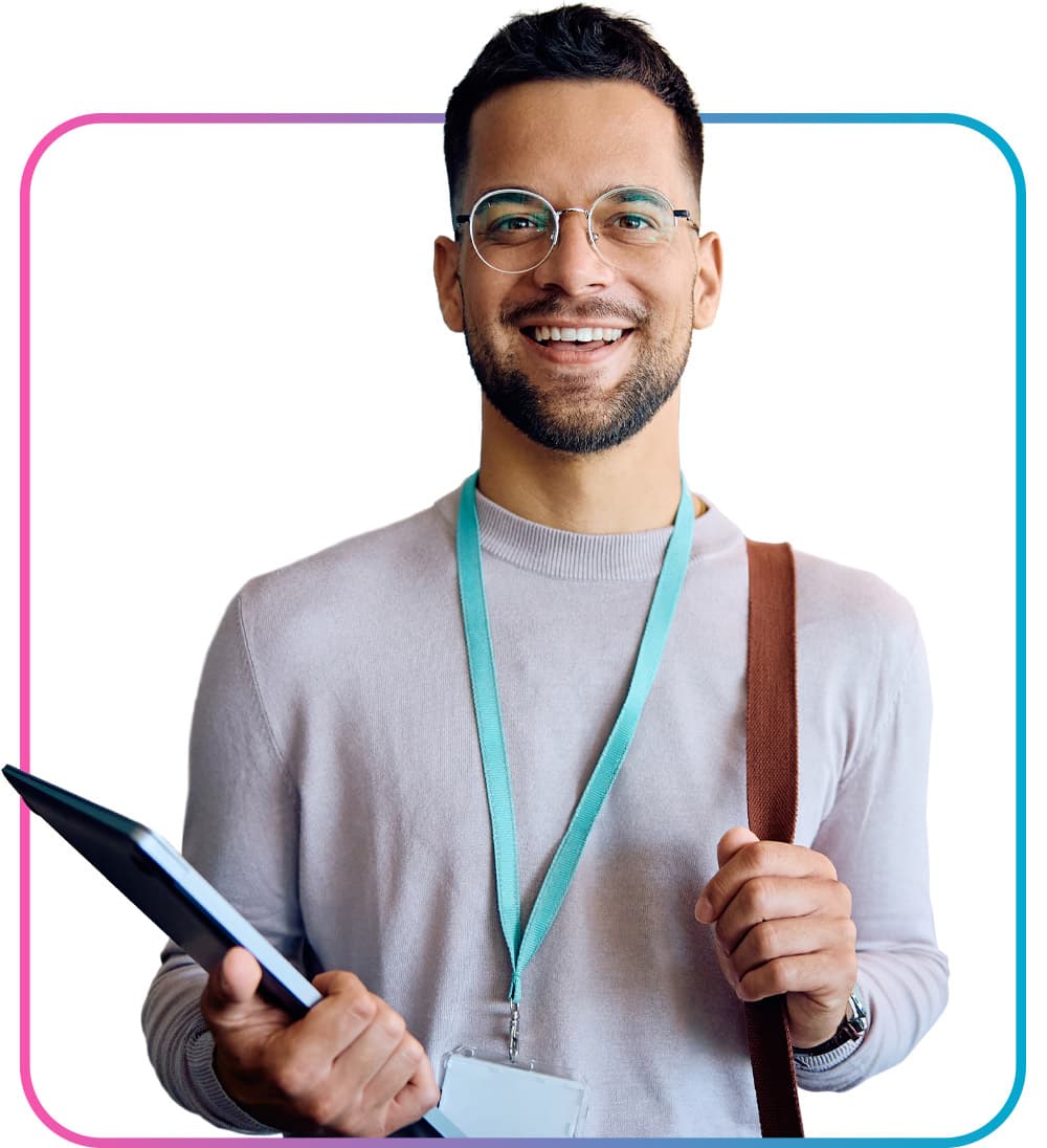 Man with lanyard holding closed laptop and clutching bag smiling