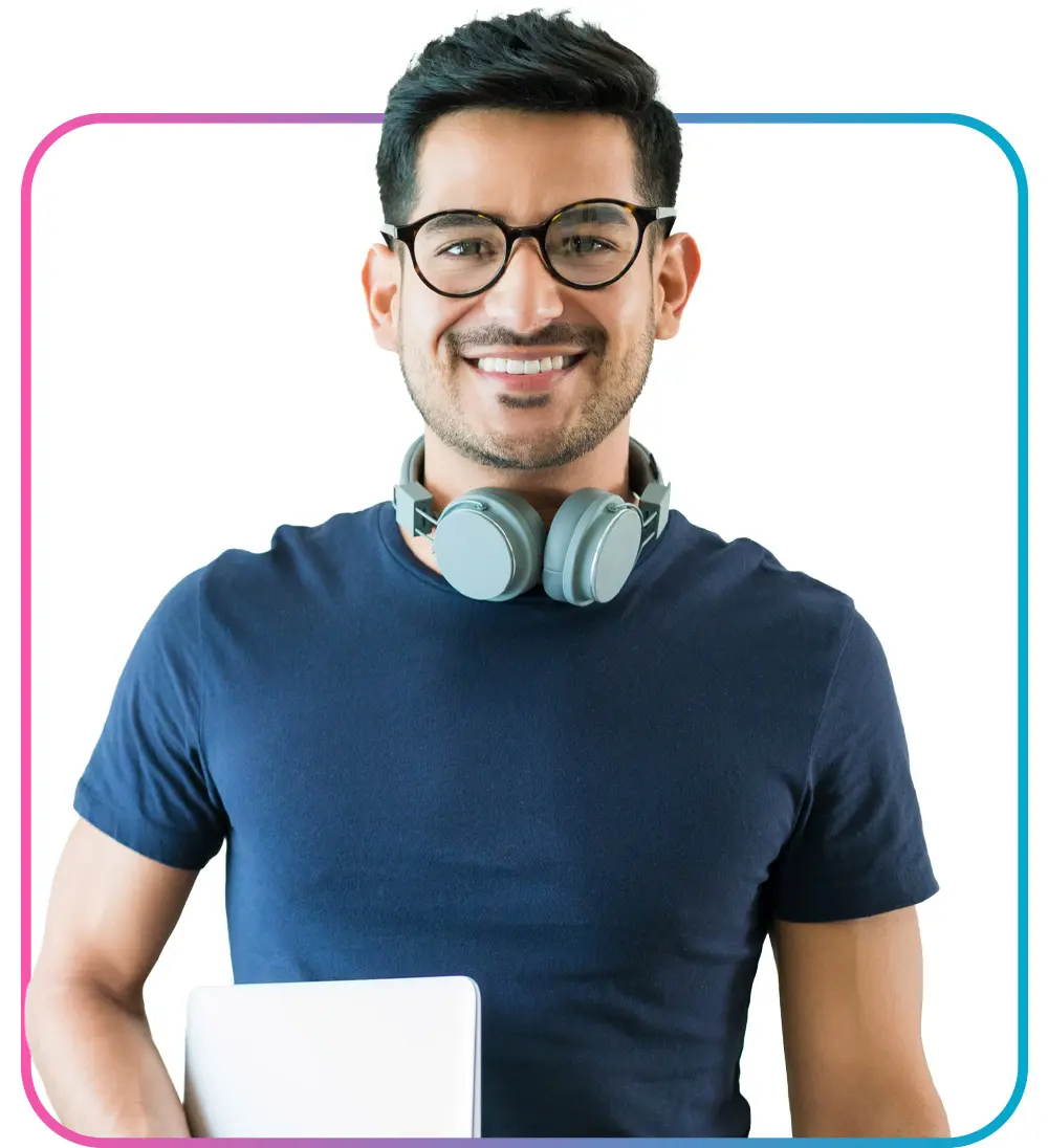 Man with headphones around neck smiling while holding closed laptop 