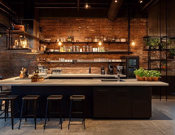 Stylish industrial kitchen interior with brick walls, black island, and warm lighting