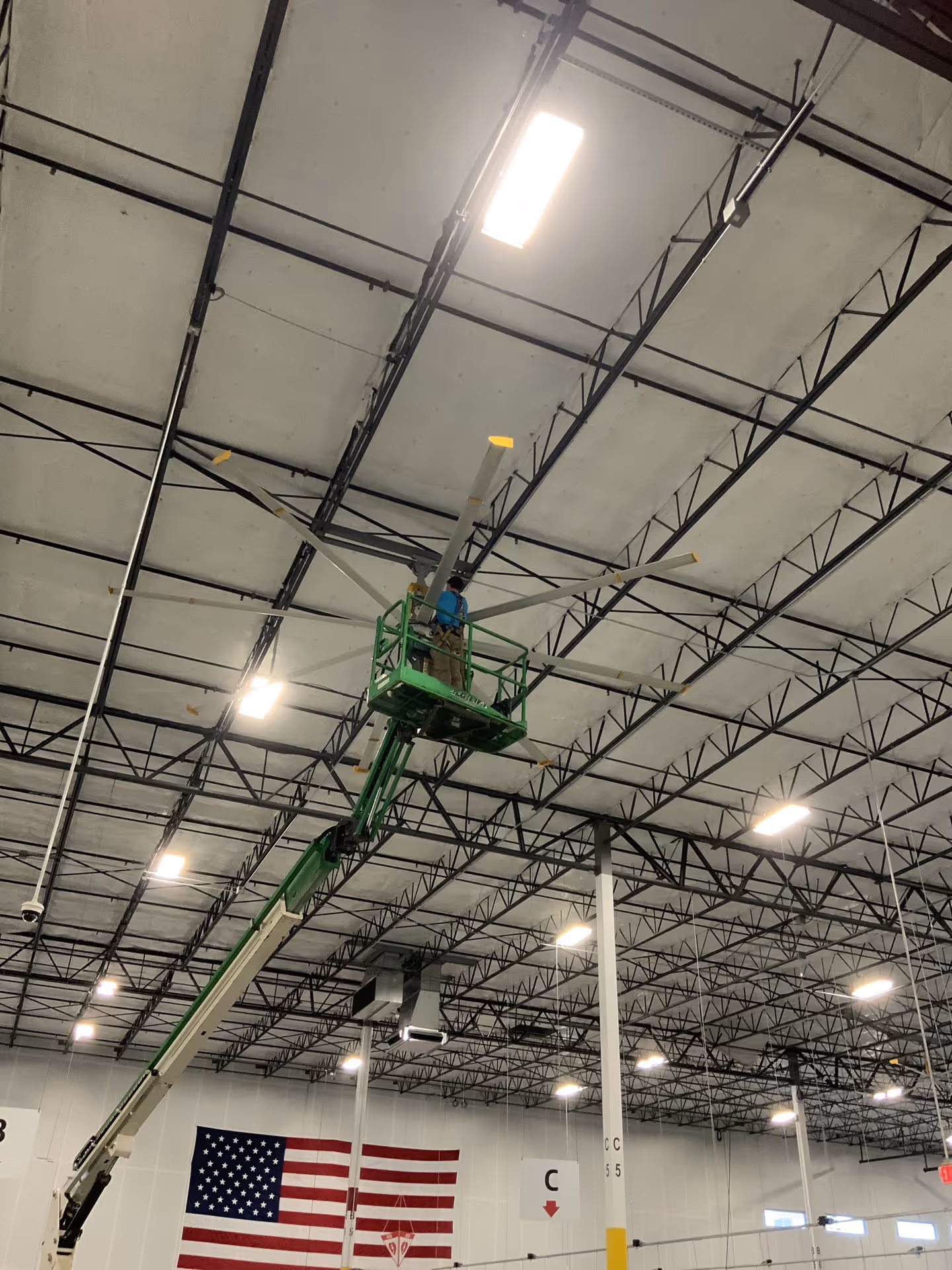 Industrial factory with workers operating machinery and a worker elevated on a blue lift platform.