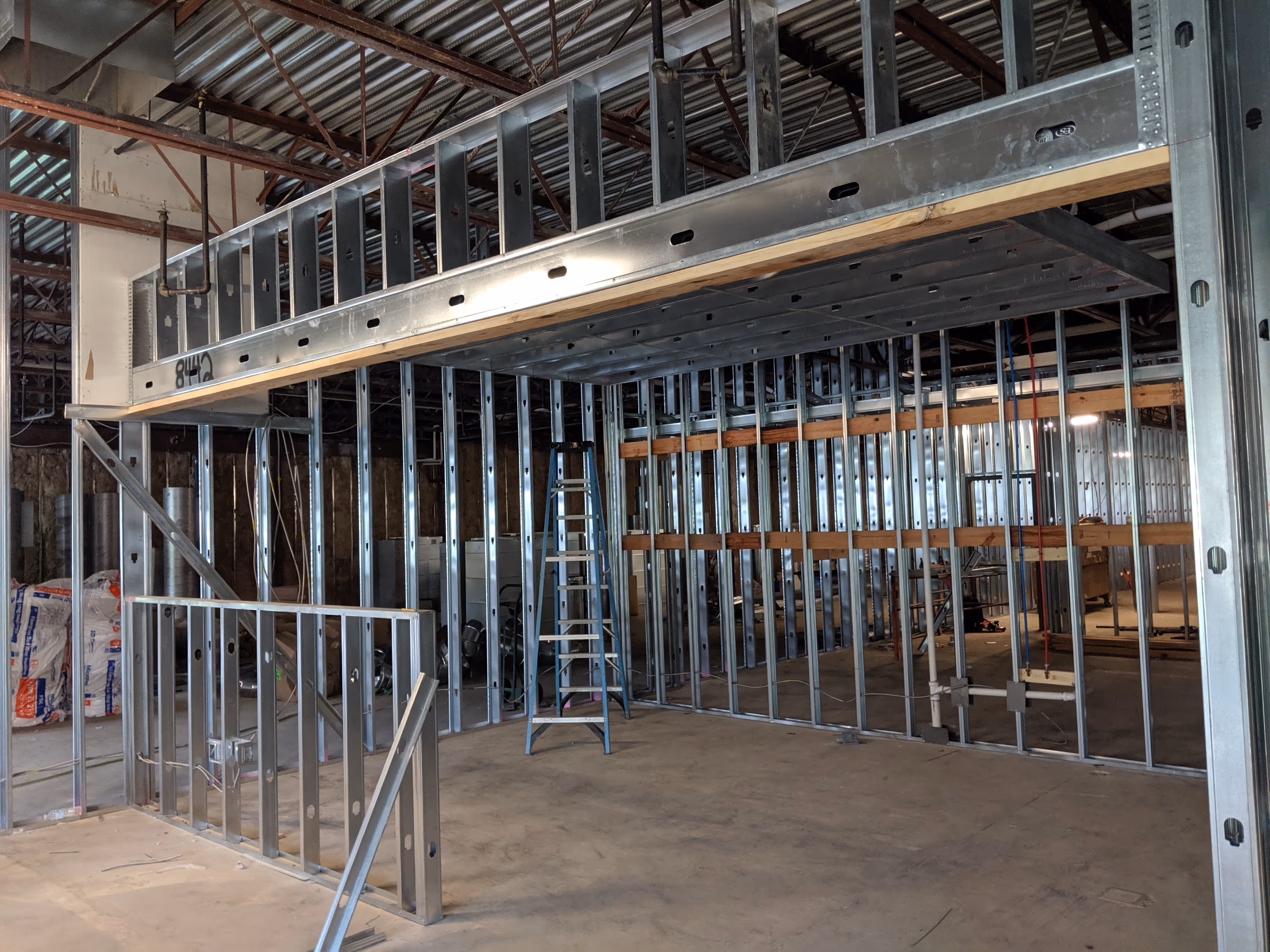 Close-up view of yellow metal scaffolding and white industrial beams against a clear sky.