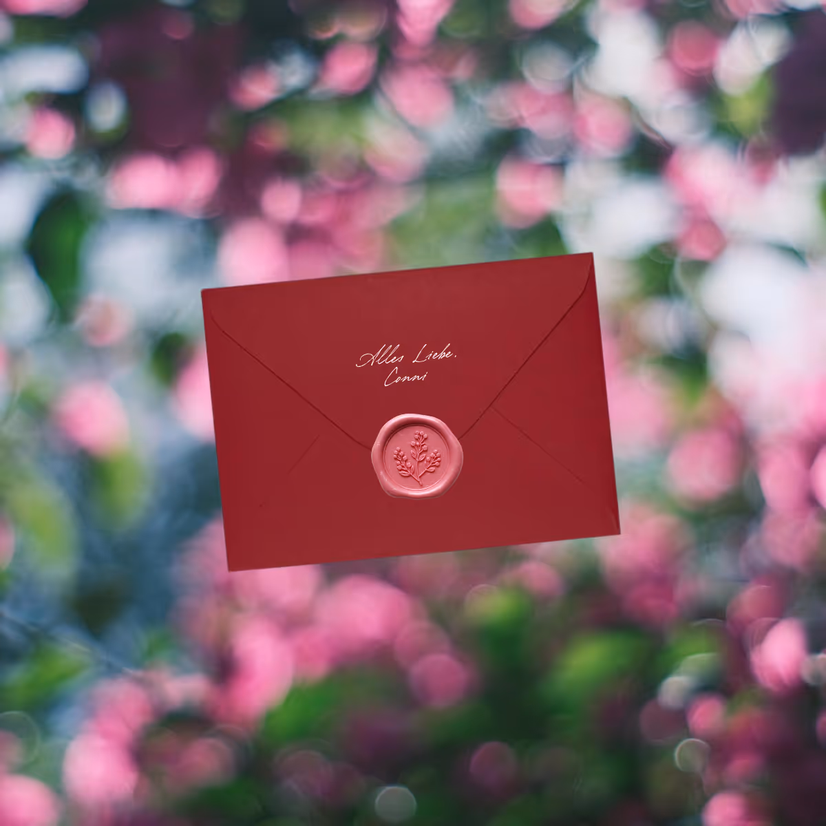 Roter Briefumschlag mit Siegel und der Aufschrift ‚Alles Liebe, Conni‘ vor verschwommenem grünen und rosa Hintergrund.
