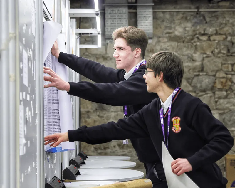 Two students in school uniforms posting their project display.