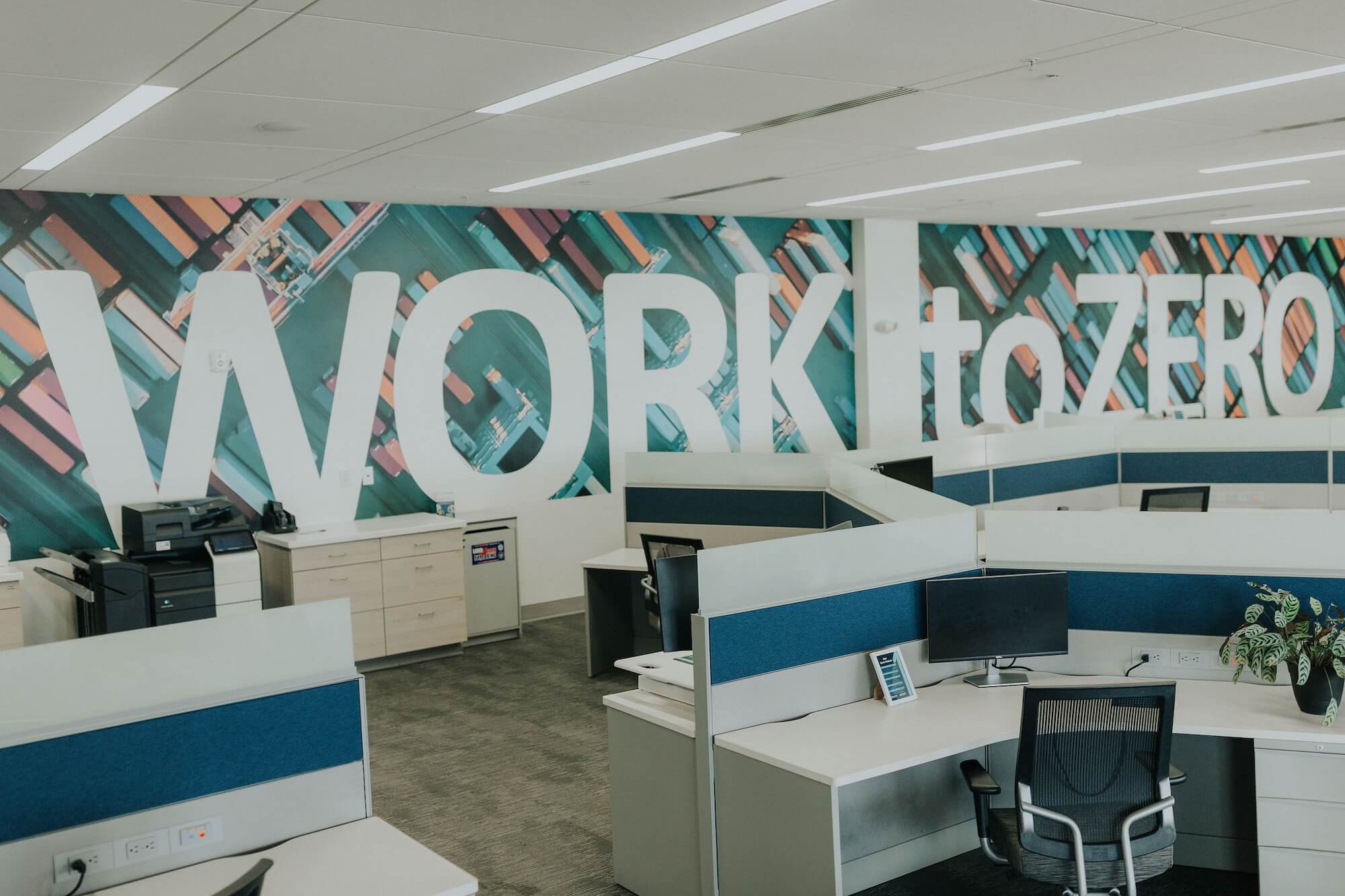 Man wearing a blue beanie and safety vest operating an orange forklift inside a warehouse.