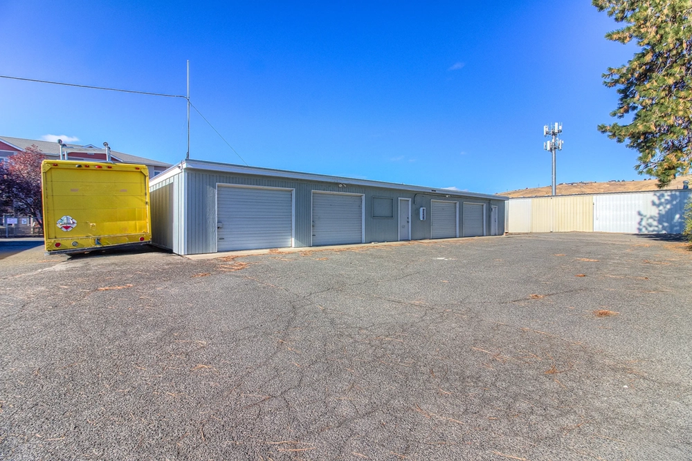 Wide paved lot at West Yakima Storage on N 34th Ave, with garage-style storage units, security fencing, and vehicle parking access.