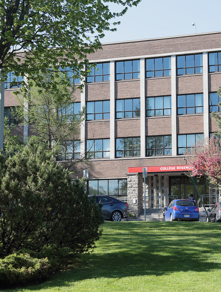 Brick college building with large windows, entrance under a red sign reading 'COLLÈGE ROSEMONT', cars parked in front, and green trees and lawn in the foreground.