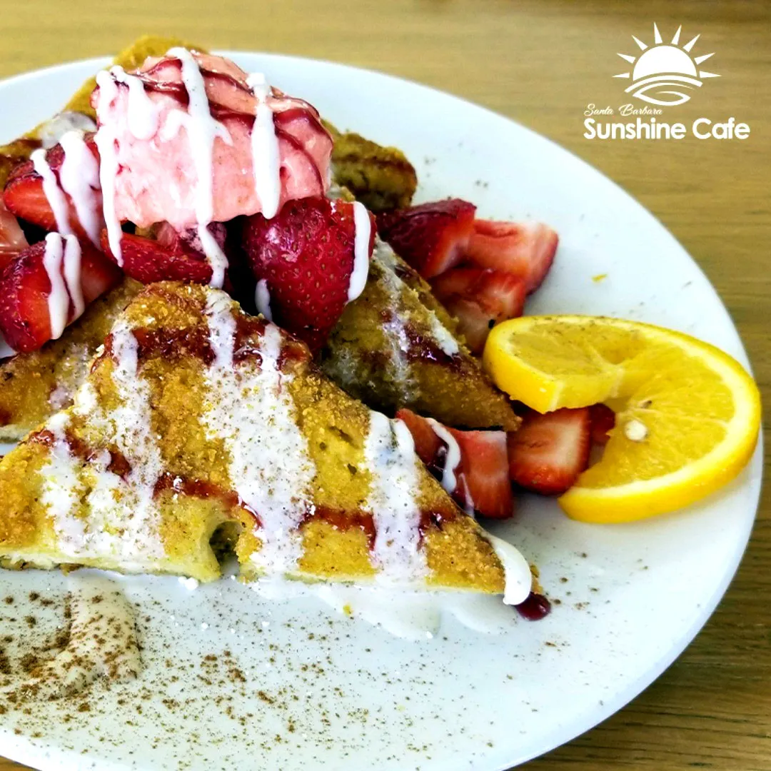 French toast with strawberries, a scoop of strawberry ice cream, and a slice of orange.