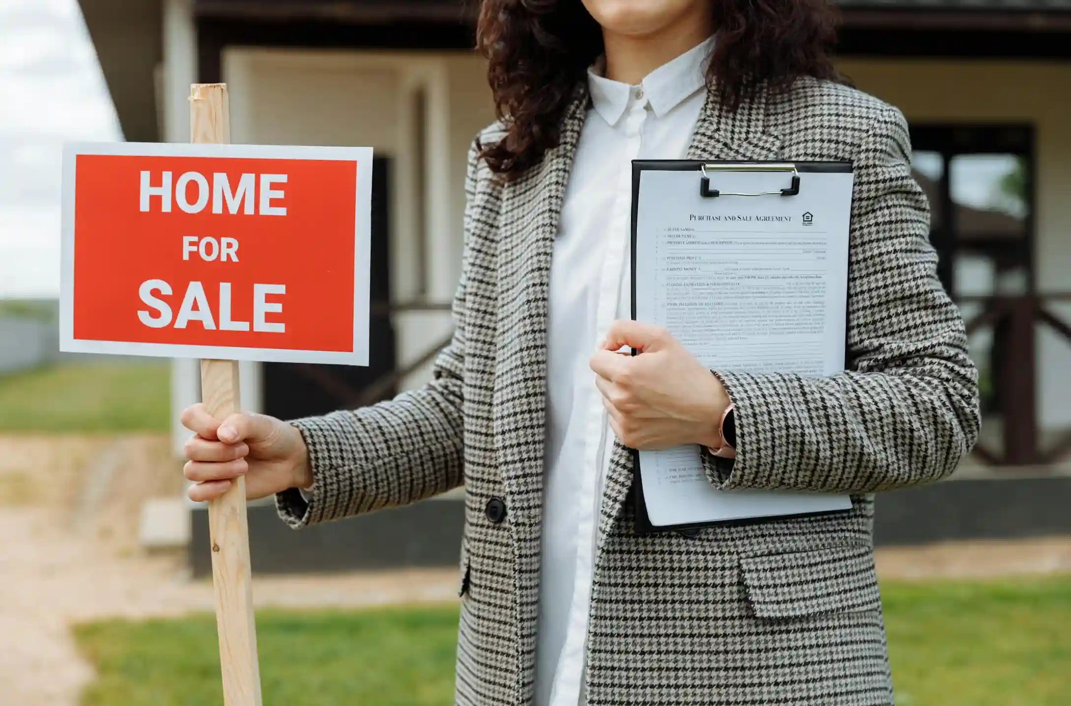 woman holding a home for sale sign