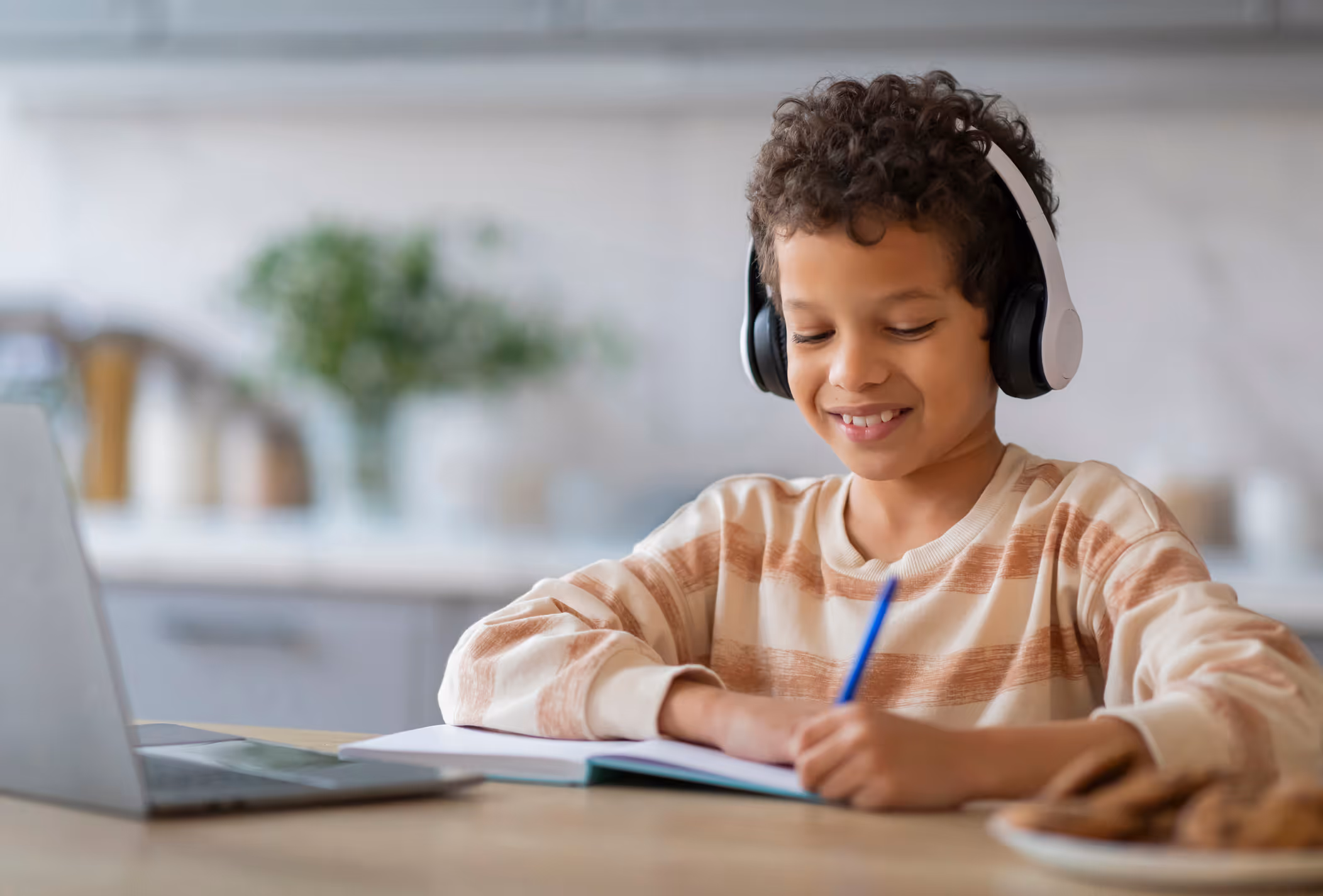 Smiling boy completing written assessment with headphones for Independent Educational Evaluation (IEE).
