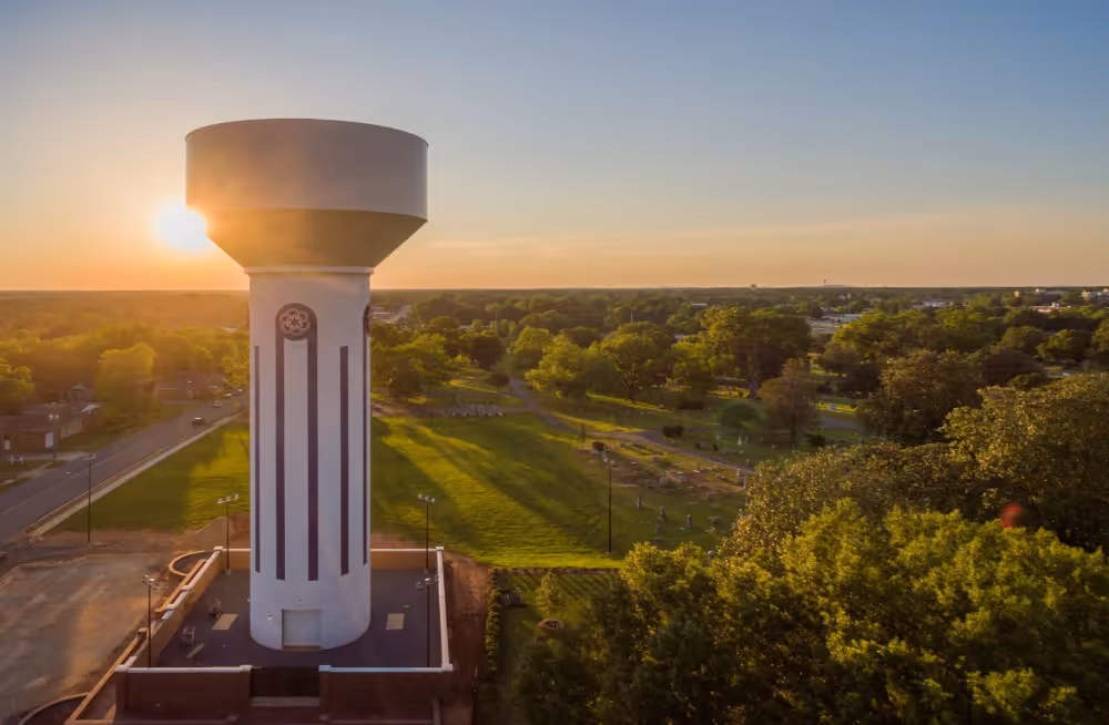 A photograph of a water tower set against a setting sun