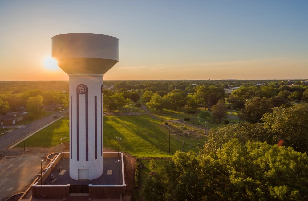 A photograph of a water tower set against a setting sun