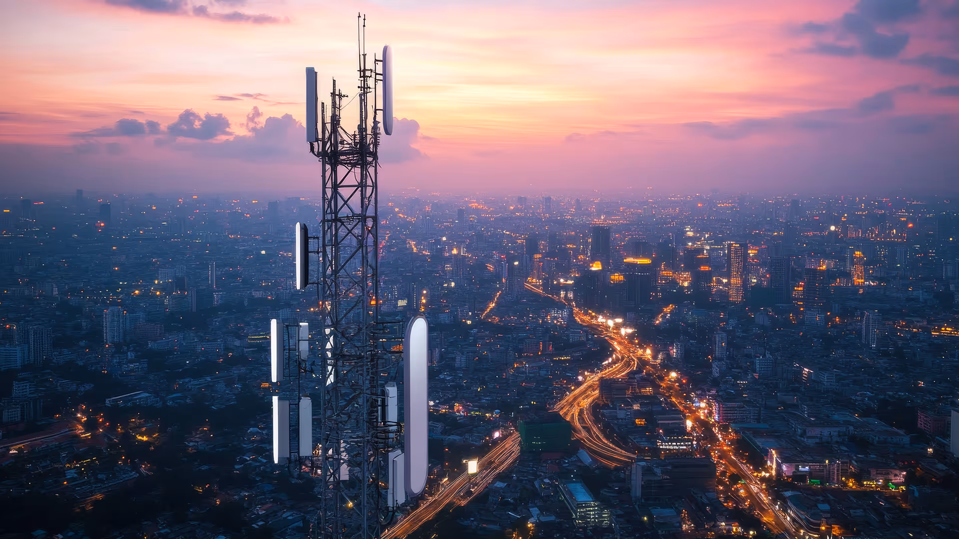 A photograph of a cell communications tower with a large city in the background