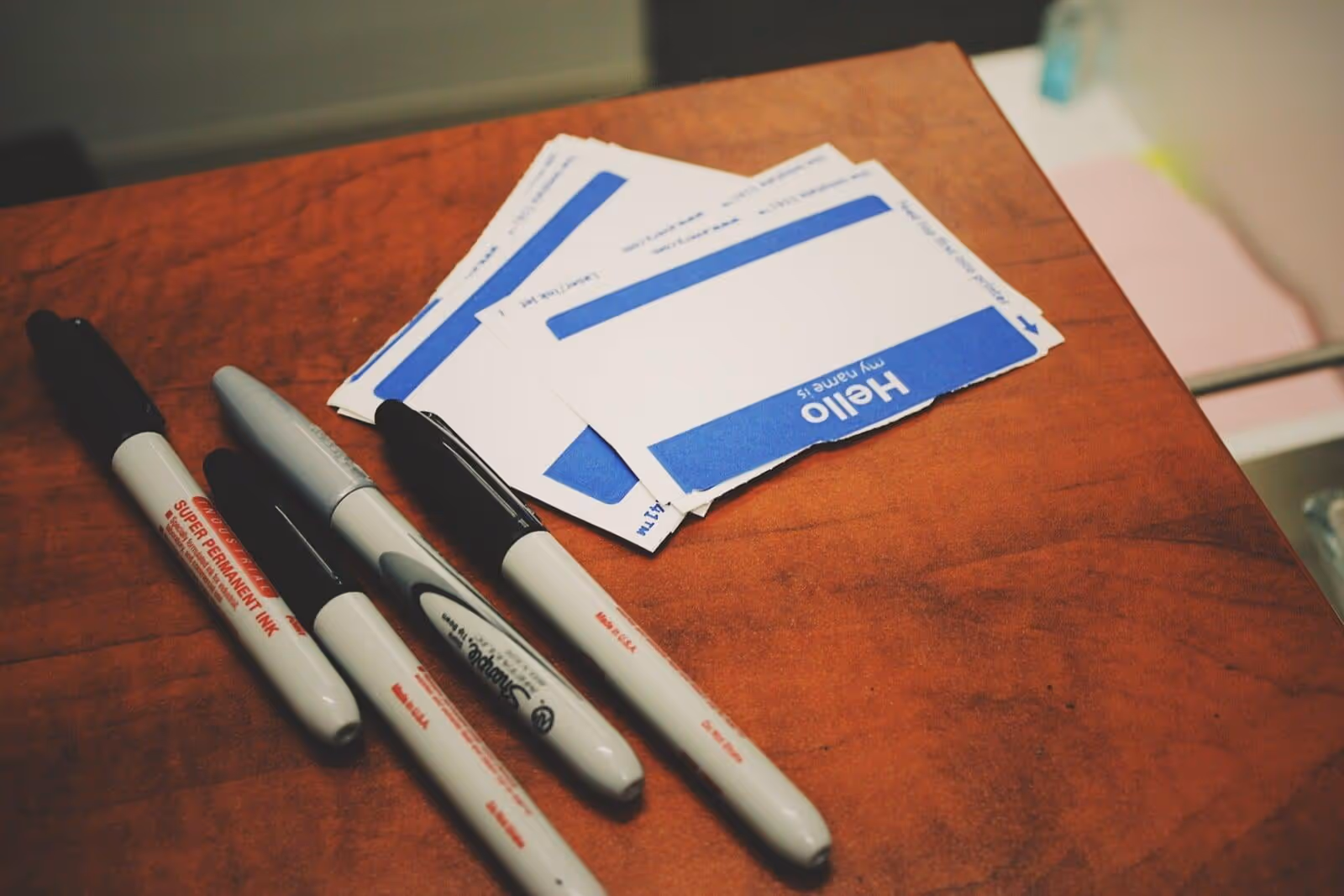 Image of sticker name tags and black markers on a table