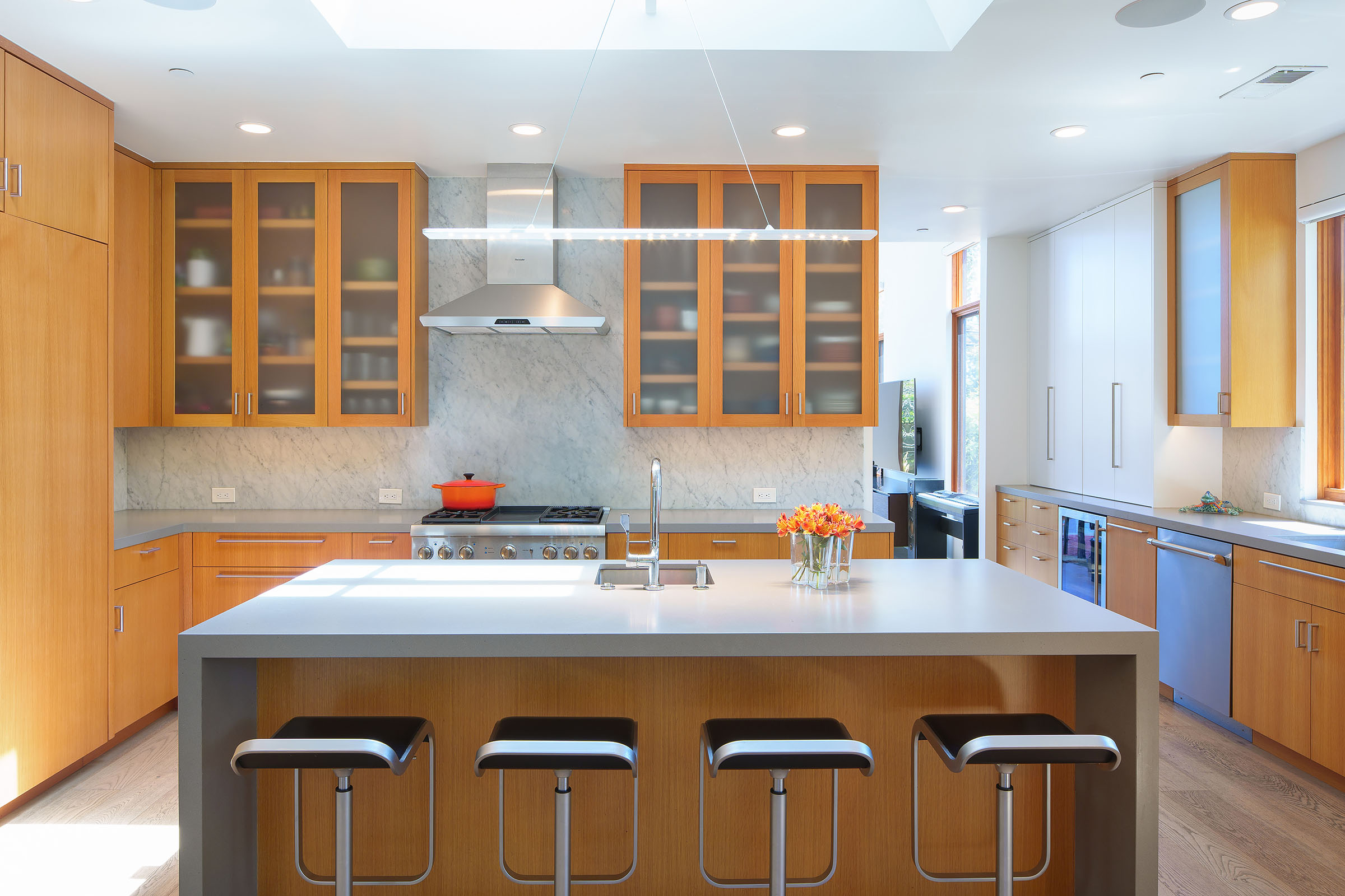 Modern open kitchen with flush oak cabinets and large skylit island with seating.