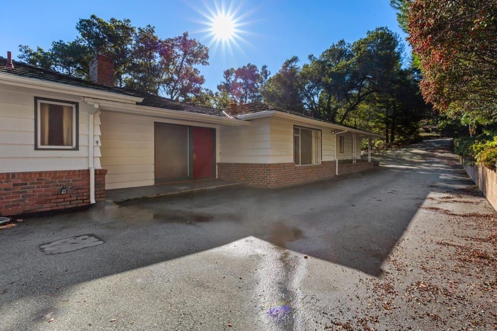 Existing single-story 1950s house set down from street level with a long driveway