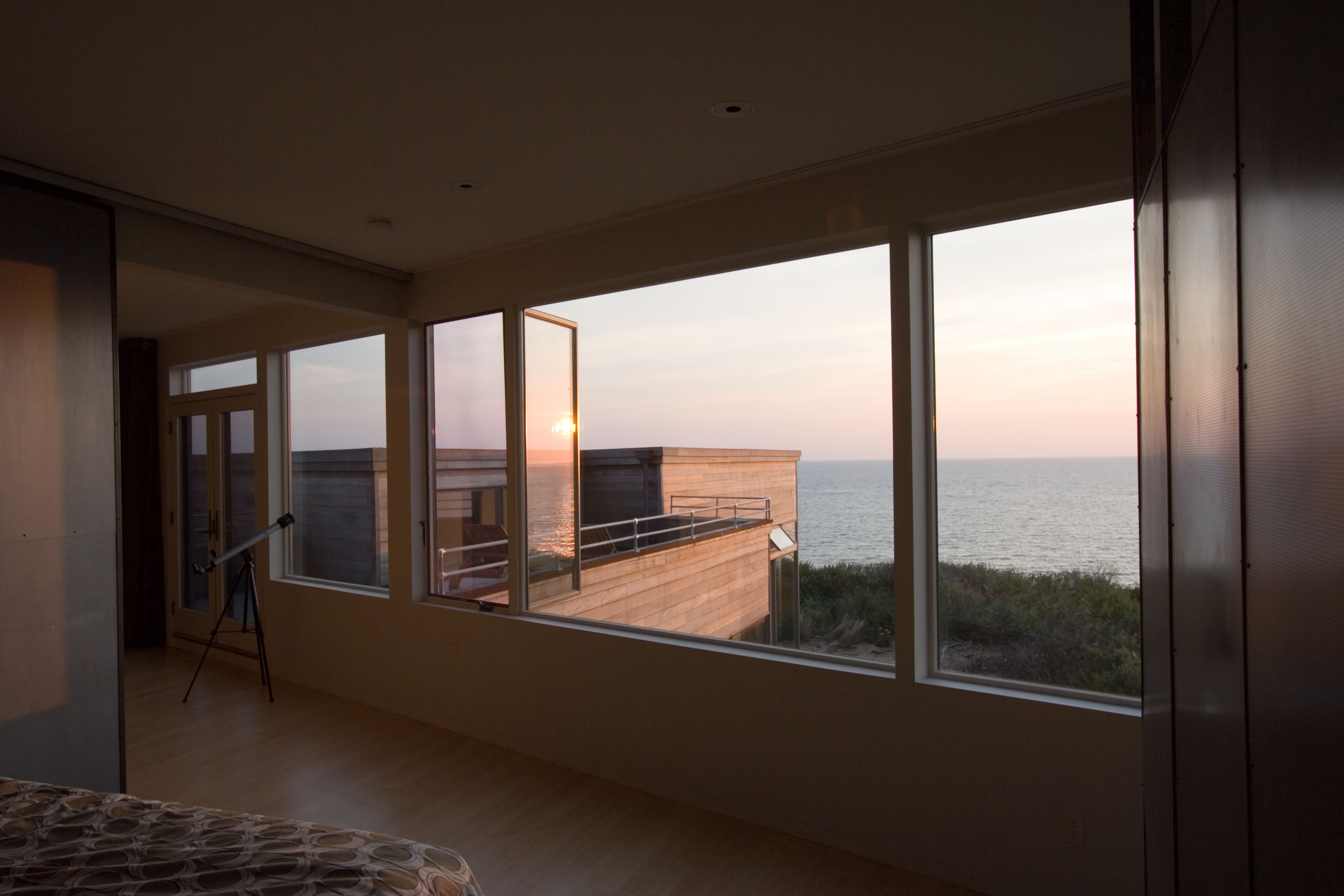 Sunset view over the ocean seen through large second story windows of the master bedroom