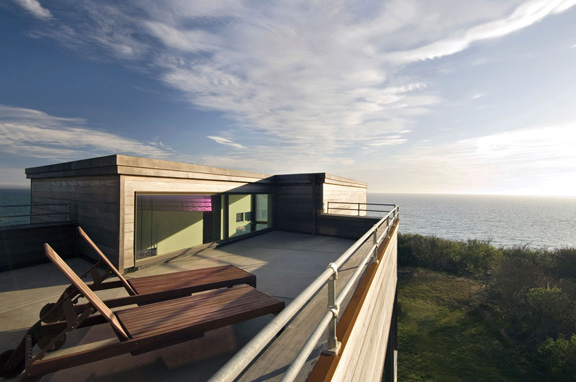 Modern rooftop terrace with two wooden lounge chairs overlooking Cape Cod Bay.