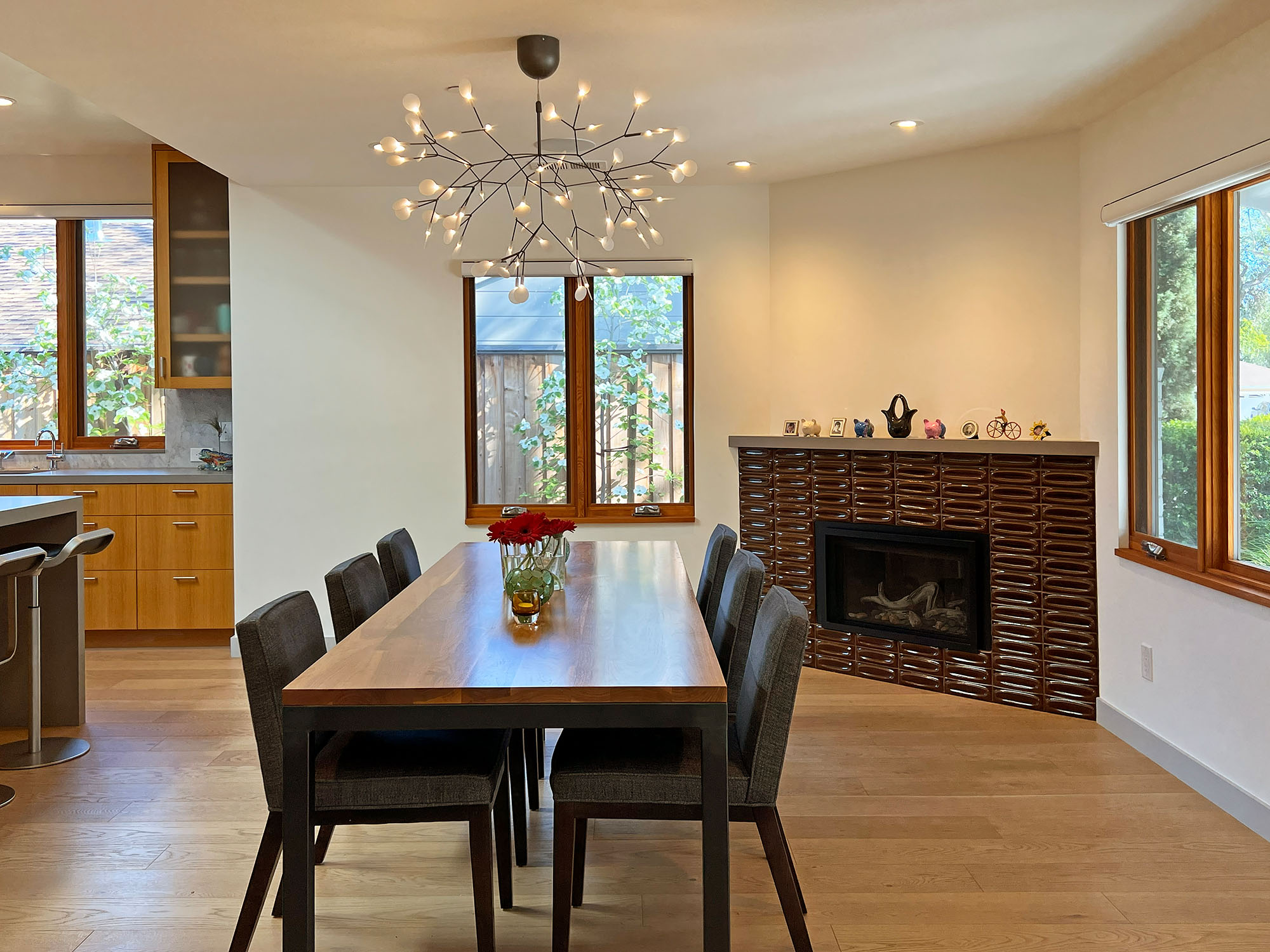 Modern dining room with Moooi chandelier, and a fireplace with dimensional Heath tiles and a mantel.