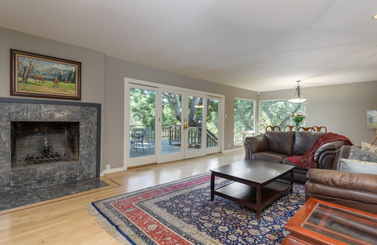 Original living room with glass doors opening to a deck, a marble fireplace, located in the middle of the house