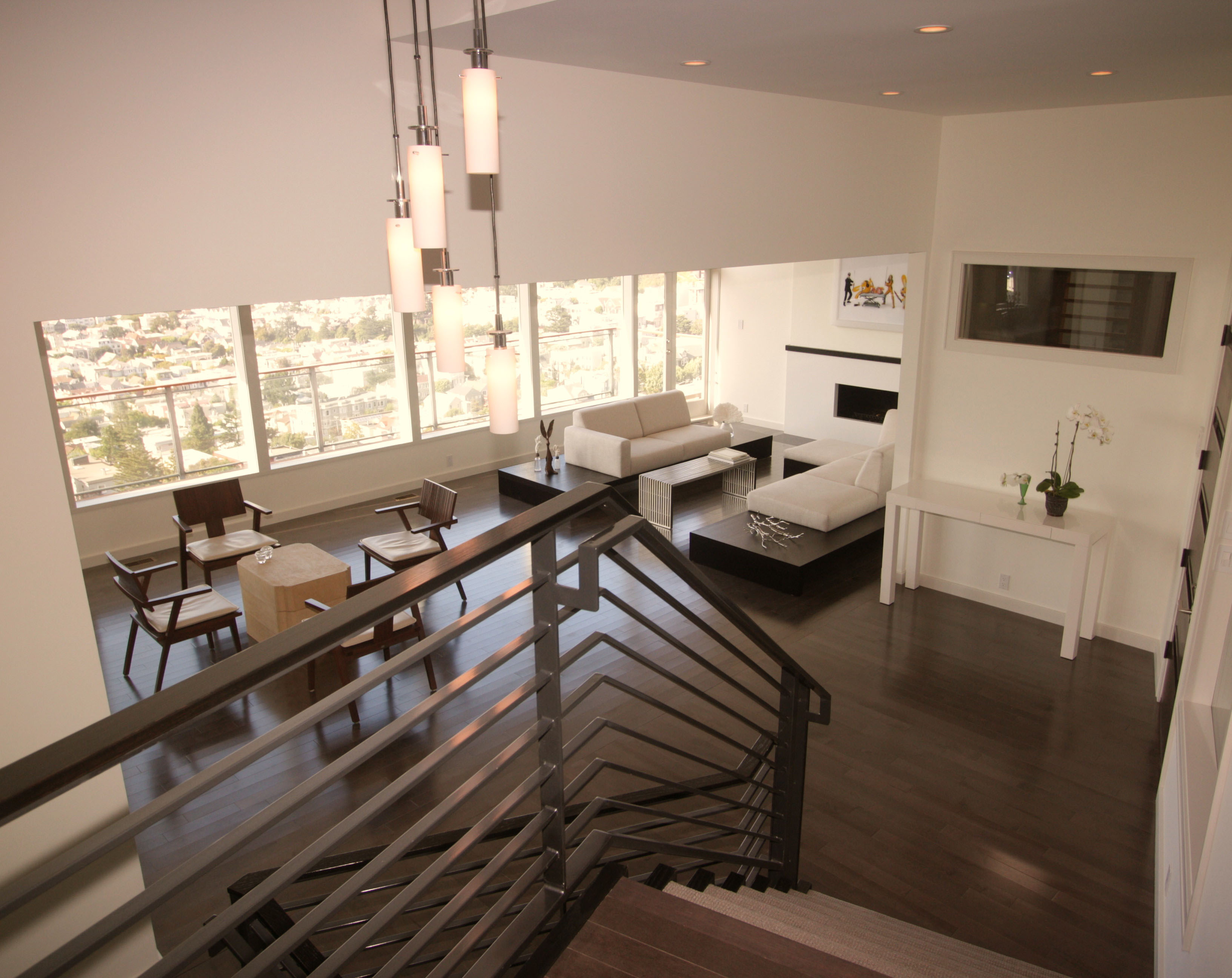 Modern living room with large windows with views of San Francisco and a metal railing staircase.