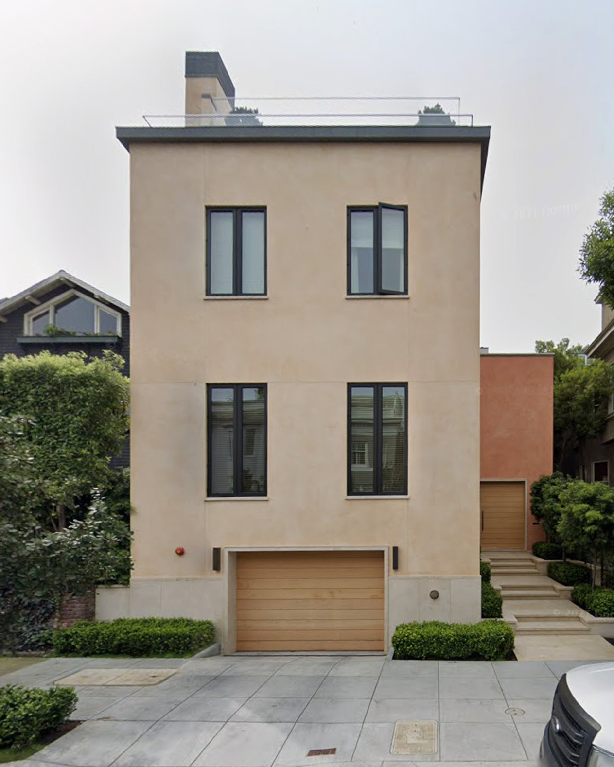 Modern three-story house in Pacific Heights with premium metal windows, wooden garage door, and cascading steps leading to a recessed entry with a large pivot door