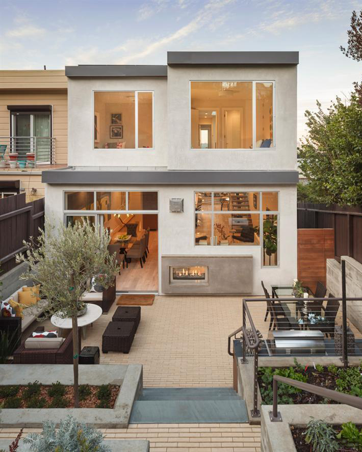 Modern two-story San Francisco house exterior with large windows, outdoor fireplace, patio seating, and landscaped garden beds.