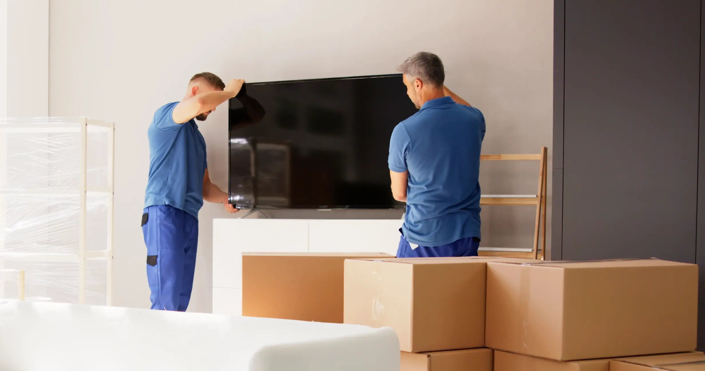 Two-man delivery team placing a television inside a customer’s home as part of V1 Distribution’s room-of-choice delivery service.