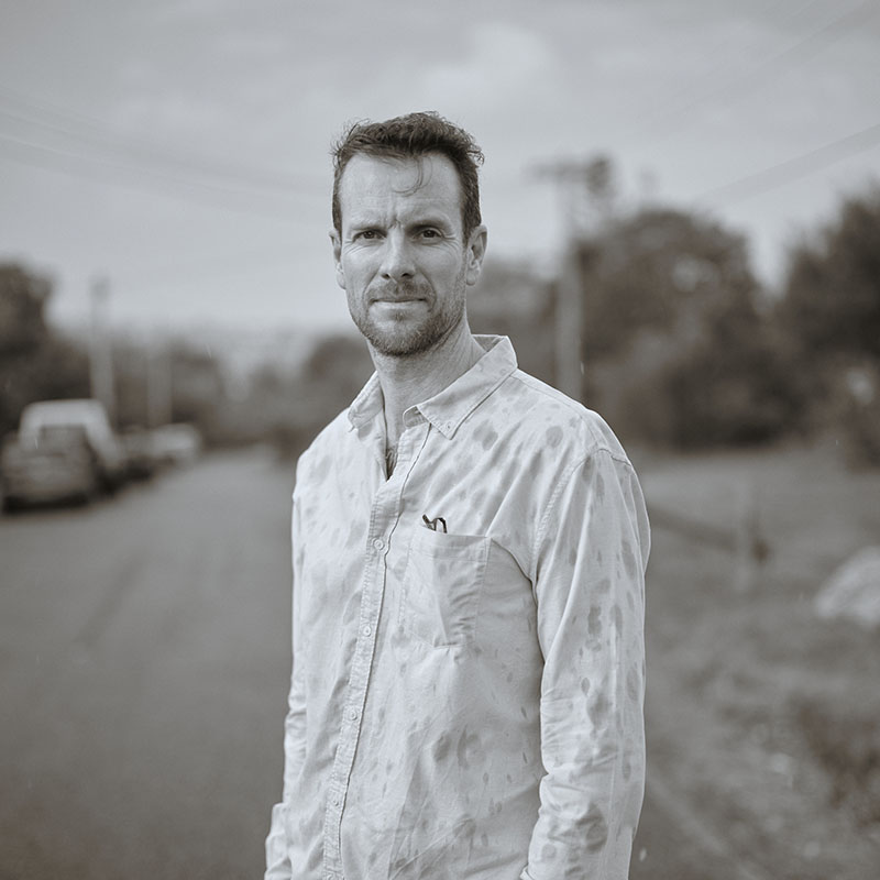 Khyal wearing a wet white button-up shirt standing on a street with blurred background.