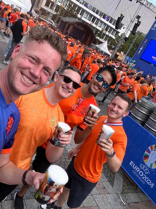 Drie mannen zitten aan een tafel met laptops en glazen water, in een moderne kantoorruimte.