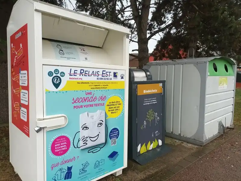 Bornes de collecte pour le textile (Le Relais), les biodéchets et le verre alignées en extérieur.