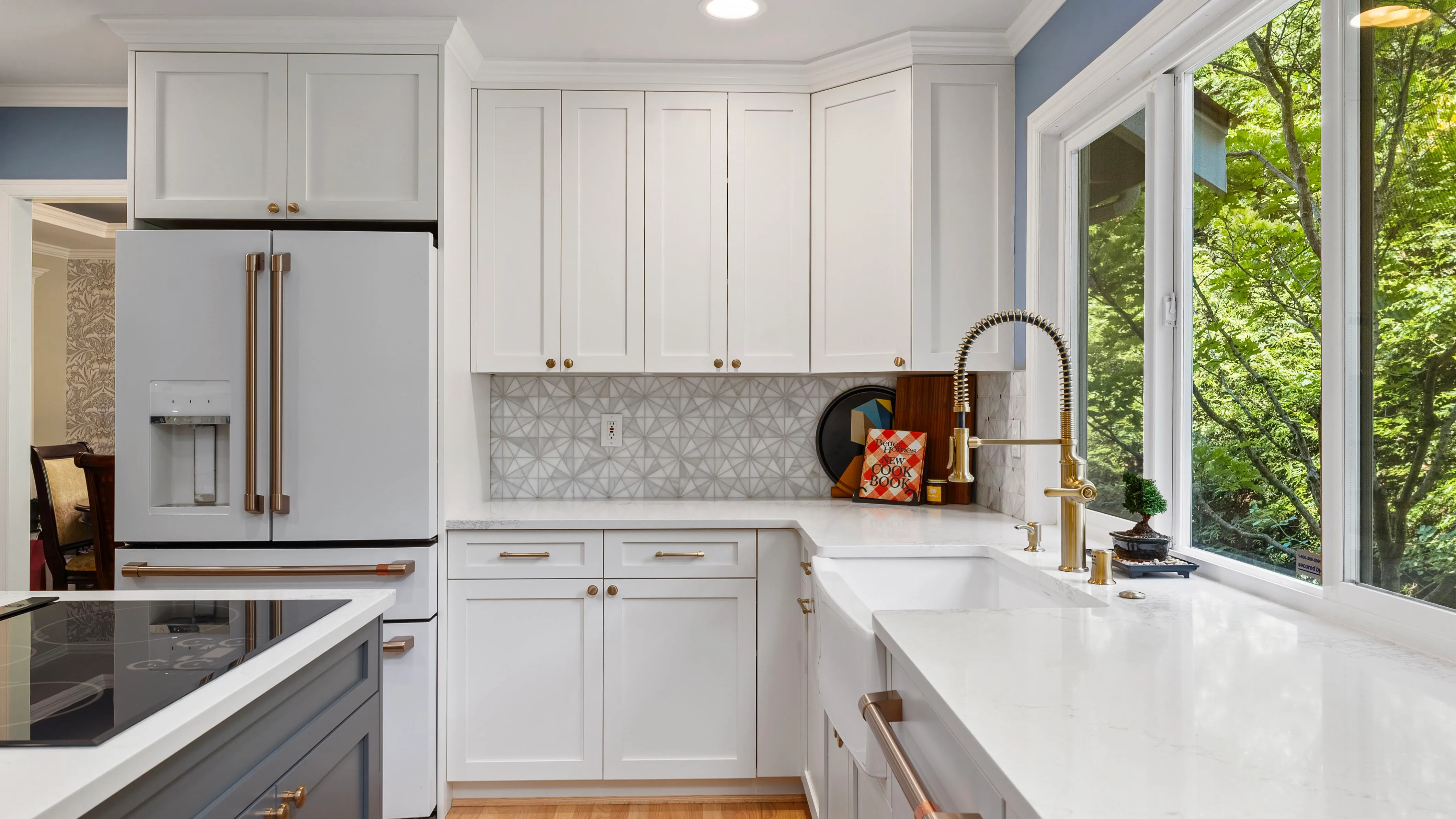 High-end remodeled kitchen with custom cabinetry, gold faucet, patterned backsplash, and quartz counters installed by Crafthaus Home Remodeling