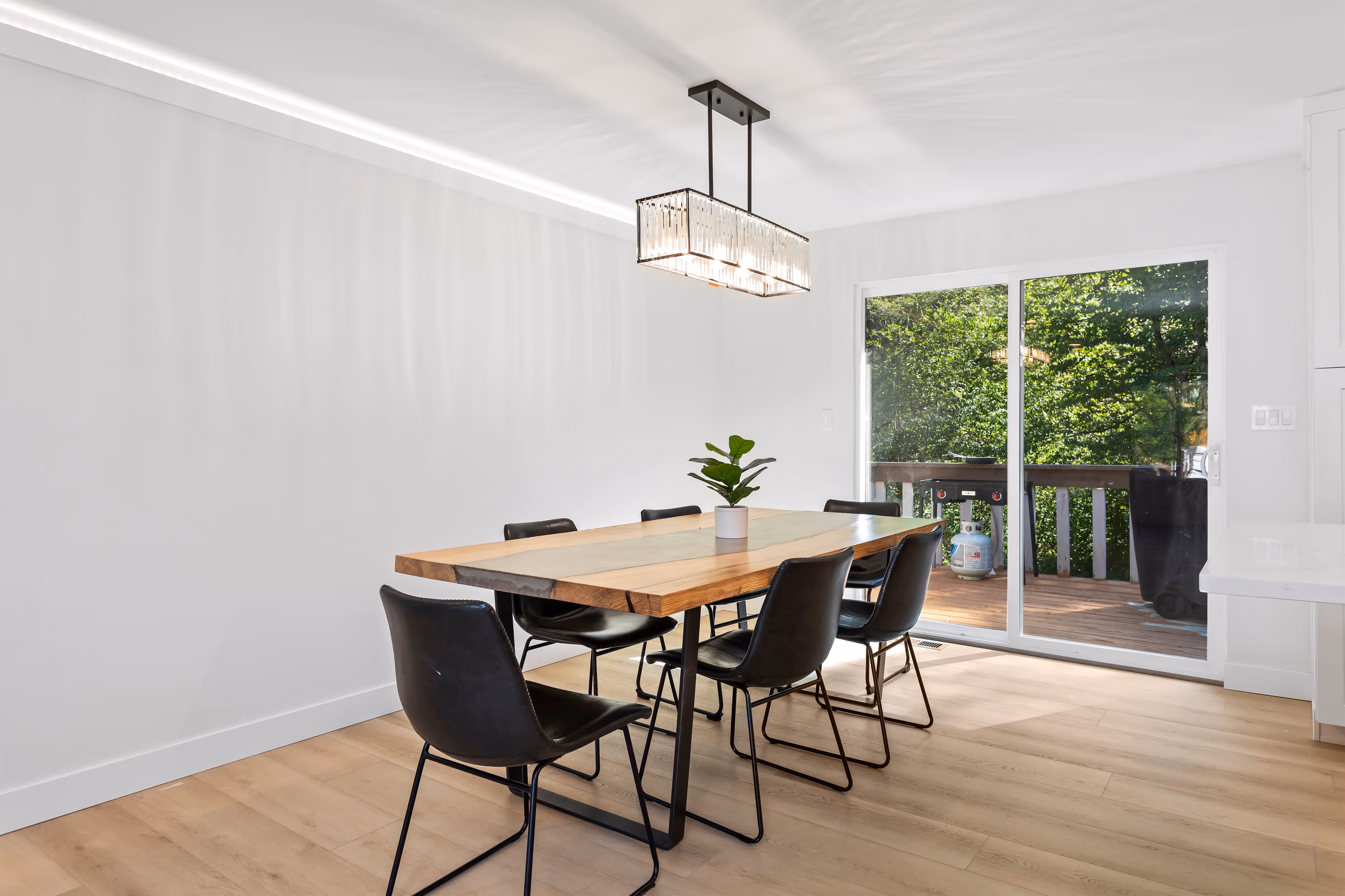 Modern dining room from a whole house remodel featuring a wood table, black chairs, updated flooring, and large sliding doors installed