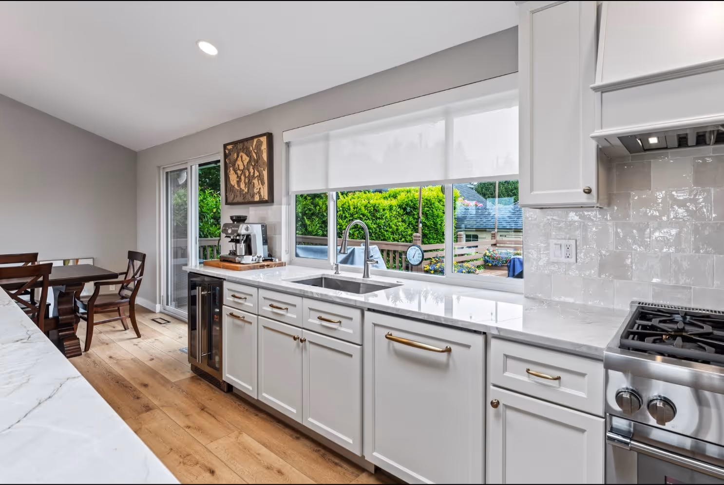 White kitchen with gold hardware, big window above sink, and coffee station