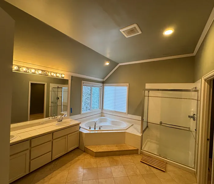 Outdated primary bathroom with old flooring, basic vanity, dated tile