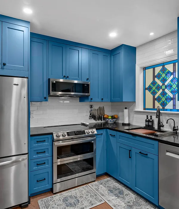 Modern kitchen with blue shaker cabinets, black countertops, and stainless steel appliances after cabinet installation remodel