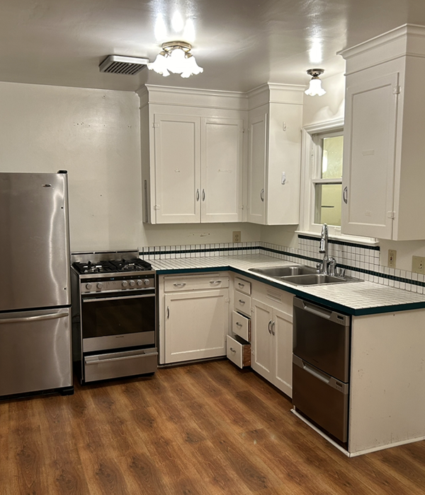 Small outdated kitchen with white cabinets, laminate countertops, and basic appliances before cabinet renovation