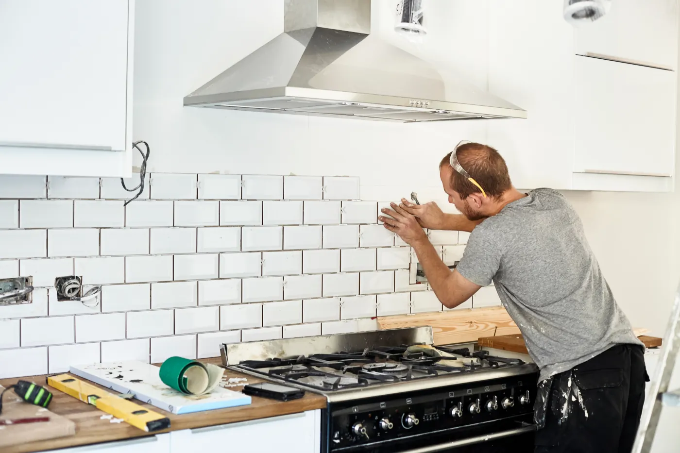 A contractor working on a kitchen backsplash touch-up during renovation