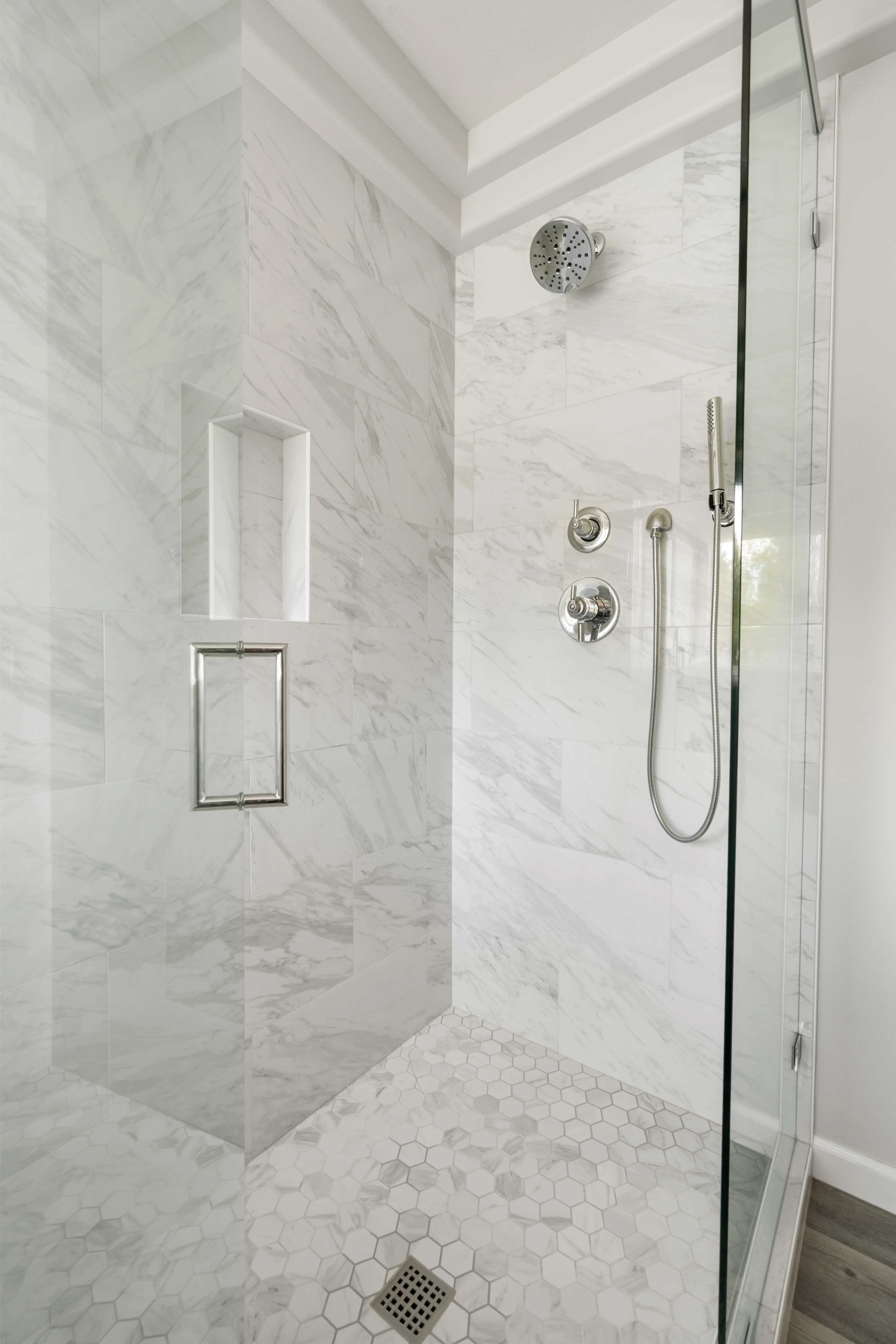 An open glass door of a walk-in shower with silver fixtures in Bothell