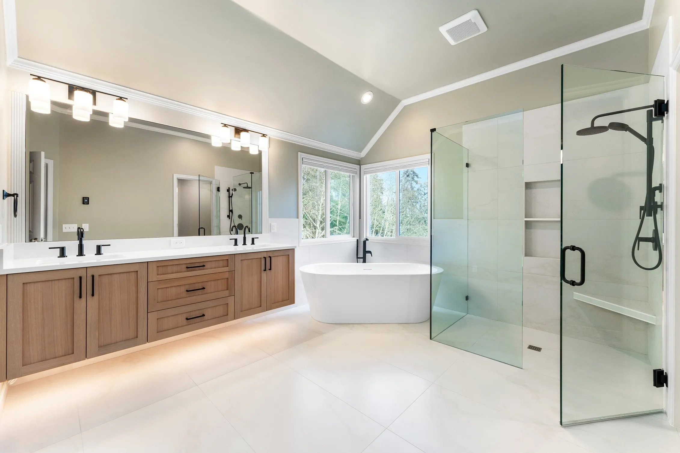 Freestanding tub in between bathroom sink with full-length mirror and walk-in shower in Bothell, WA