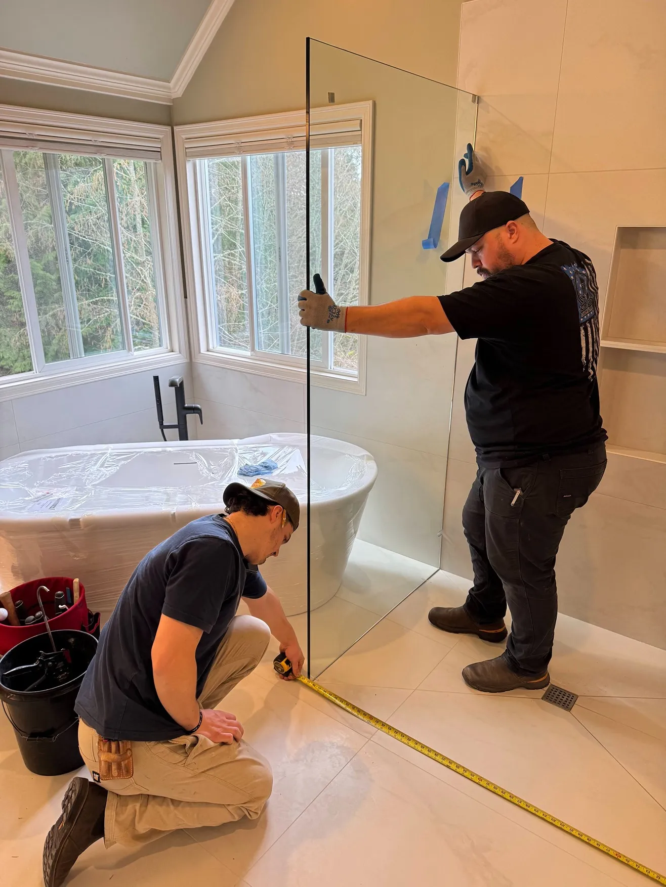 CraftHaus remodeling contractors installing glass walls for walk-in shower in Bothell